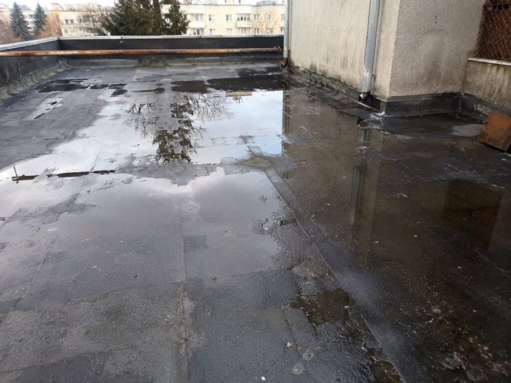 Băltiri de apă pe o terasă după ploaie cauzate de o pantă insuficientă și drenaj deficitar